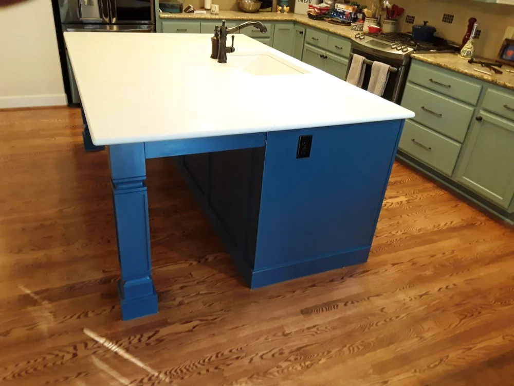 A blue kitchen island with a white countertop in LLN’s published project gallery